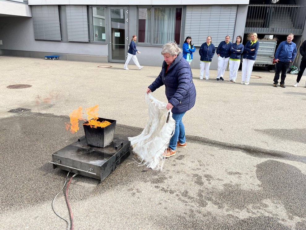 In bestimmten Fällen kann das Feuer kann auch mit anderen Hilfsmitteln als einem Feuerlöscher gelöscht werden, wie es Mitarbeiterin Andrea Glanz mit einer Löschdecke demonstrierte. 
