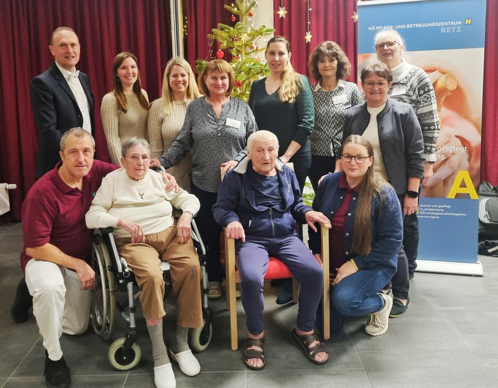 BILDTEXT 1 Das Weihnachtsfest im PBZ Retz war stimmungsvoll und liebevoll gestaltet – vlnr.: Pflegeassistent Walter Fasching; Kaufmännischer Direktor Horst Winkler, MBA; Sängerin Daniela Mayer; Bewohnerin Ernestine Rockenbauer; Sängerin Pia Häckel; Ehrenamtliche Mitarbeiterin Gertrude Stift; Bewohner Erich Auer; interim. Pflegedirektorin Astrid Günes; Ehrenamtliche Mitarbeiterin Christine Mauthner; Managerin Ehrenamt und Alltagsbegleitung Isabella Schimak; Obfrau Verein Cogo Michaela Pabst; Managerin Ehrenamt und Alltagsbegleitung Sabine Ernst-Frischauf
