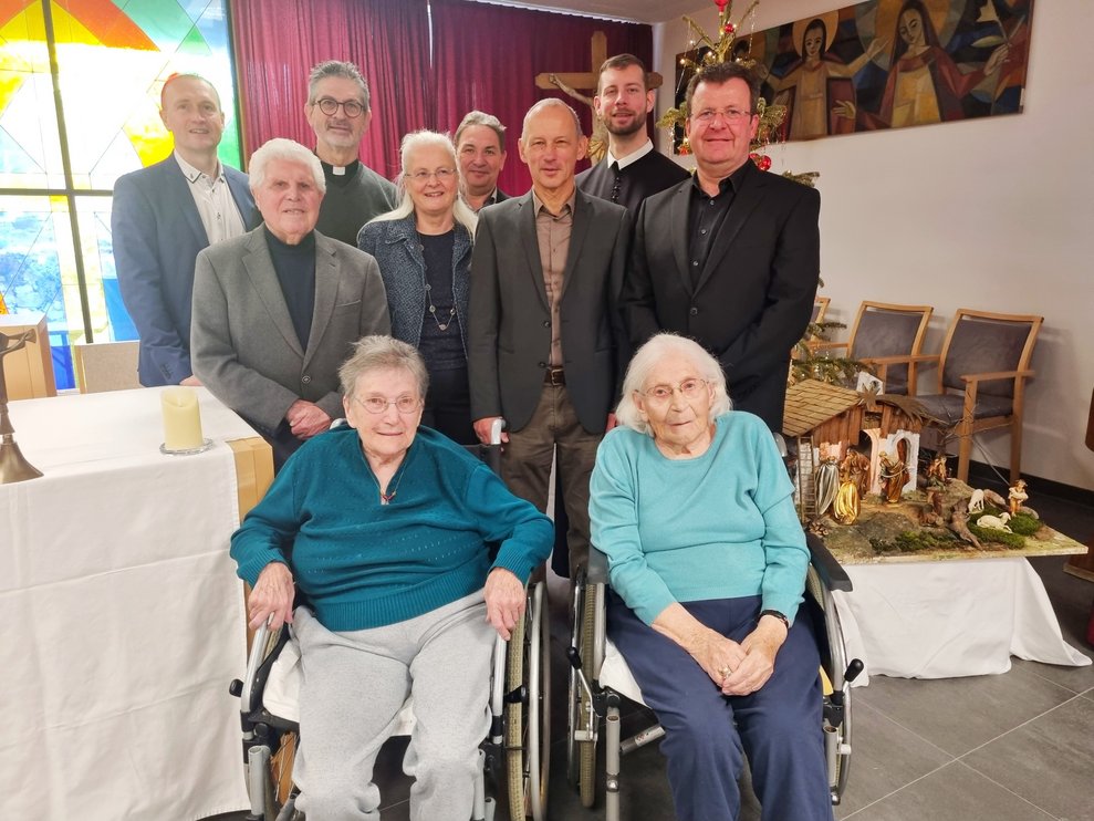 Auch die Bewohnerinnen Ernestine Rockenbauer und Elfriede Bischinger (vorne vlnr.) genossen den Gottesdienst und die Weihnachtslieder gesungen vom Retzer Gesangsverei – stehend vlnr.: Kaufm. Dir. Horst Winkler, MBA; Adolf Hofstetter; Diakon Mag. Christian Suchy; Agnes Opitz; Thomas Schmid; Obmann Peter Steurer; Pater Johannes Paul; Dirigent Ernst Kölbl